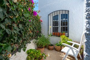 A white wall with a window, potted plants, and a white chair. - Los Pinos 25 Villas by Casasol (Nerja)