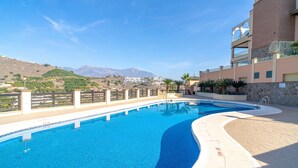 A swimming pool with clear blue water, surrounded by a paved deck and a stone wall. - Tamango Hill Alcazaba B by Casasol (Torrox)