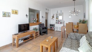 A living room with a sofa, TV, wooden coffee table, and a dining area with chairs and a table. - Tamango Hill Alcazaba B by Casasol (Torrox)