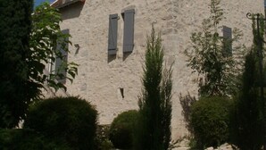 A stone building with a symmetrical facade, multiple windows, and a small balcony.