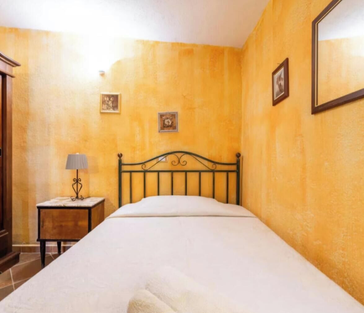 A bedroom with a bed, a nightstand with a lamp, and two framed pictures on the wall.