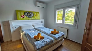 Ein Schlafzimmer mit Bett, Fenster und Wandklimaanlage.