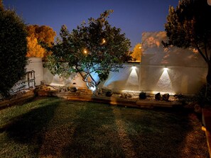 A garden with a tree, a water feature, and a stone wall.