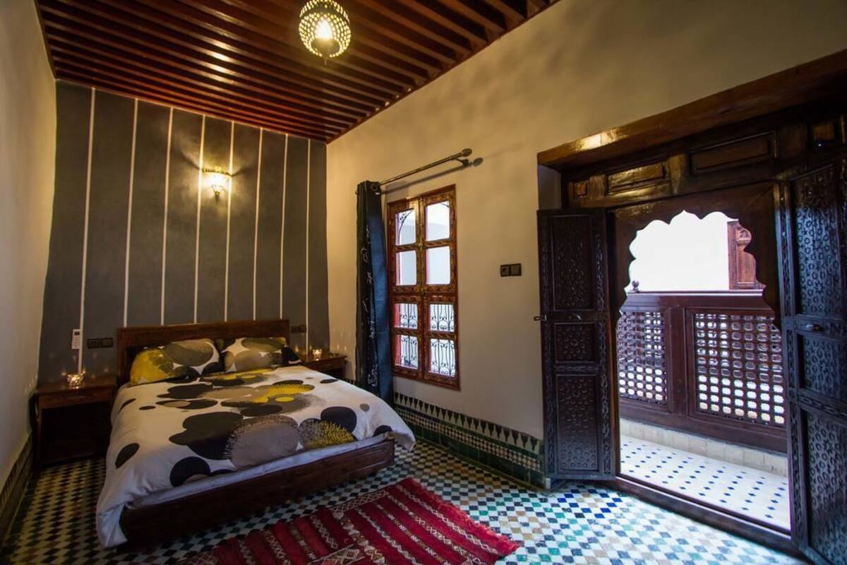 Un dormitorio con cama, ventana con vistas y puerta que da al exterior.
