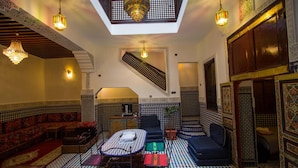 A traditional Moroccan interior with a checkered floor, ornate furniture, and a staircase leading to an upper level. - Dar el Mathaf (Fes)