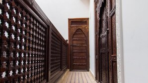 A narrow hallway with patterned tile flooring and wooden doors. - Dar el Mathaf (Fes)