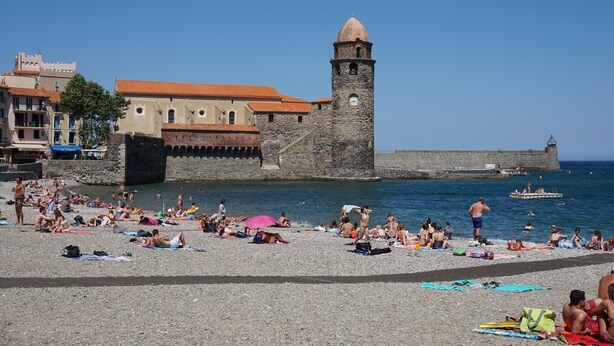 A beach with people sunbathing and swimming, a historic stone tower, and buildings with red-tiled roofs. - Apartment/ flat - COLLIOURE (Collioure)