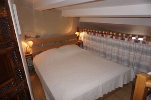 A bedroom with a wooden bed, a nightstand with a lamp, a wooden wardrobe, and a window with curtains. - Apartment/ flat - COLLIOURE (Collioure)