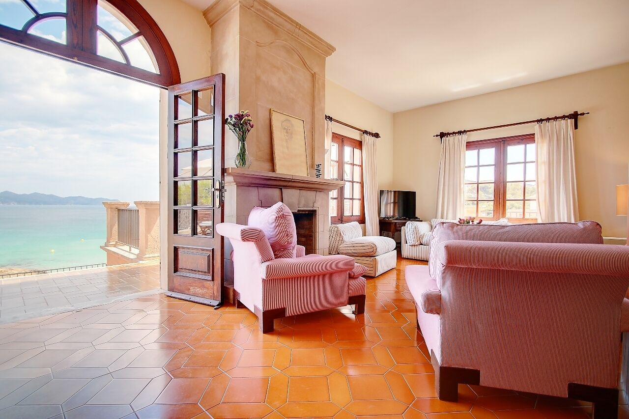 A spacious room with a large window overlooking a scenic view, a fireplace, and a cozy seating area with striped sofas.