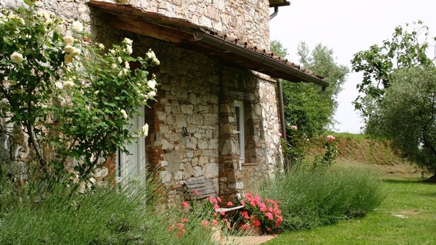 A stone building with a rustic appearance, surrounded by lush greenery and flowering plants. - Tuscan house in idyllic scenic tranquility in hills between Lucca and sea WiFi   (torcigliano)