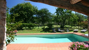 A swimming pool with a tiled deck, surrounded by a wooden fence and lush greenery. - Tuscan house in idyllic scenic tranquility in hills between Lucca and sea WiFi   (torcigliano)