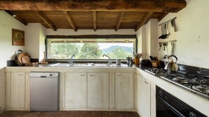A kitchen with wooden cabinets, a dishwasher, a stove, and a window with a view of greenery. - Tuscan house in idyllic scenic tranquility in hills between Lucca and sea WiFi   (torcigliano)