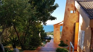 Un sendero que lleva a un edificio de paredes de piedra y vista al mar.