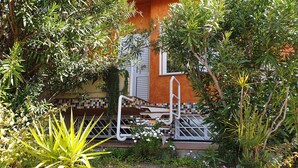 Un edificio con fachada de tejas, una escalera con barandilla y abundante vegetación circundante.