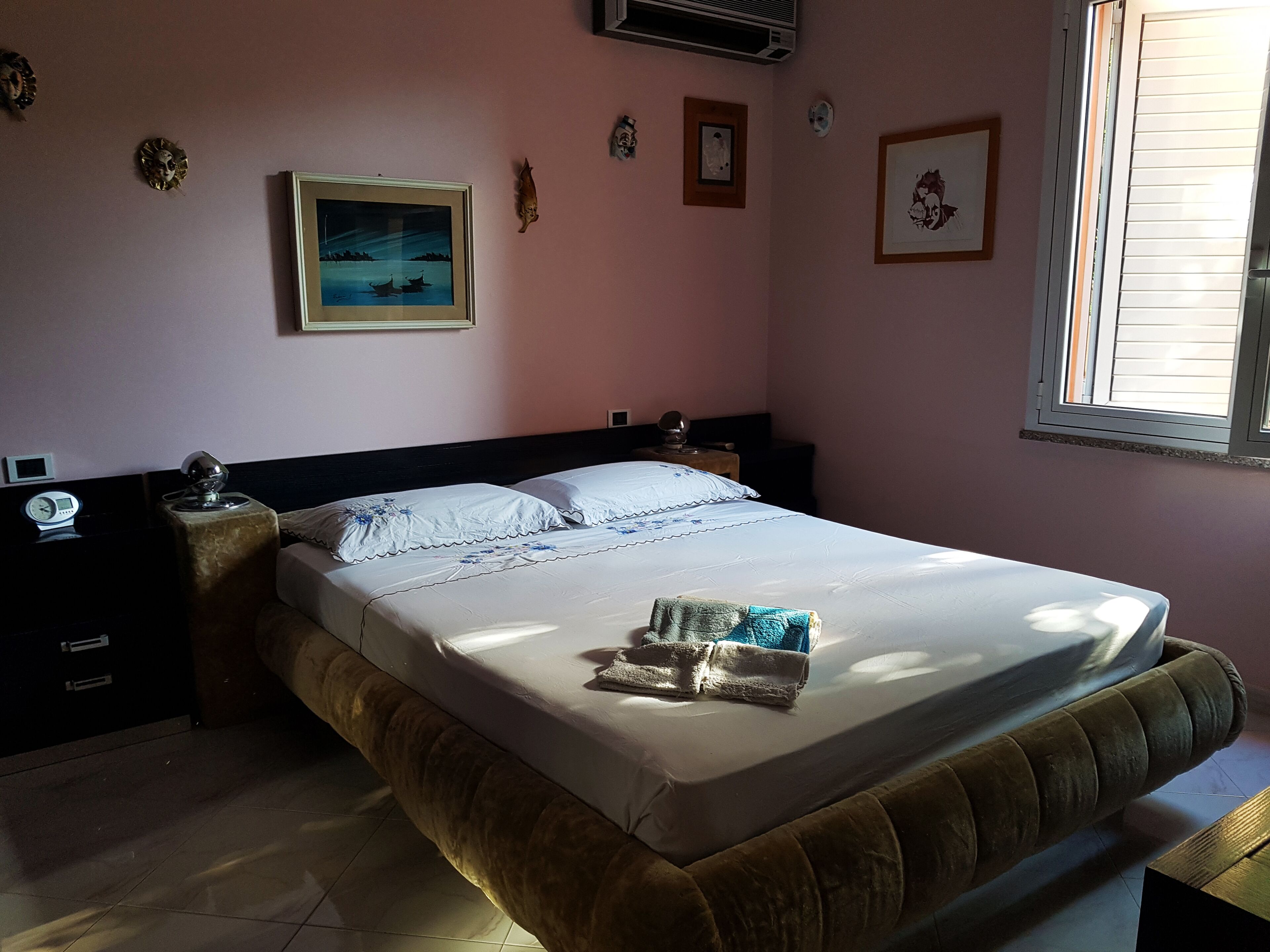 Ein Schlafzimmer mit Bett, Nachttischen, einer Uhr und Wanddekorationen.