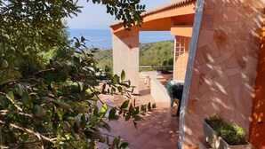 Un patio con vistas al mar, muros de piedra y una mesa con sillas.