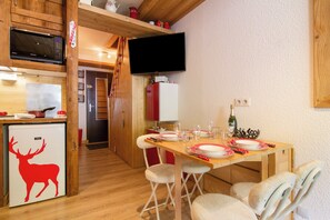 A compact kitchen with a microwave, refrigerator, and a dining area with a table set for two.