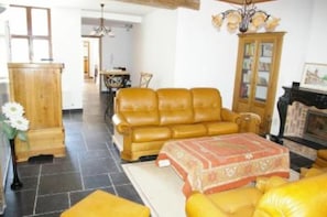 A living room with a leather sofa, a wooden cabinet, and a patterned rug. - Character house with private heated swimming pool not overlooked and jacuzzi  (Peruwelz)