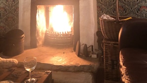 Una habitación con chimenea, papel tapiz estampado, un reloj y una cesta de mimbre.
