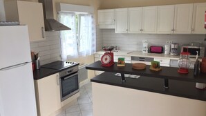 A kitchen with white cabinets, a black countertop, a stove, a sink, and a window with curtains.