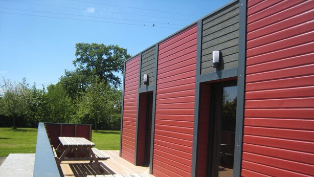 A modern building with a red exterior and a wooden deck.