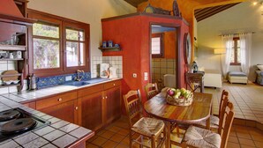 A kitchen with wooden cabinets, a tiled backsplash, and a dining area with a wooden table and chairs. - Villa Kentavros Fully private pool villa away from it all! (Skopelos)