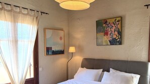 A bedroom with a bed, a hanging light fixture, a painting, and a lamp. - Villa Kentavros Fully private pool villa away from it all! (Skopelos)