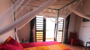 A bedroom with a bed, a chair, a small table, and a window with curtains. - Beautiful detached villa with a view over Klein Bonaire. (Santa Barbara, Kralendijk)