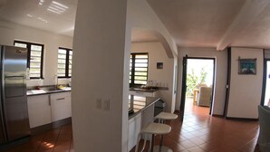 A modern kitchen with a refrigerator, sink, and bar stools. There is a window providing natural light and a view of the outdoors. - Beautiful detached villa with a view over Klein Bonaire. (Santa Barbara, Kralendijk)