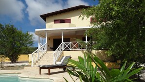 A poolside area with a lounge chair, a staircase leading to a balcony, and a pool. - Beautiful detached villa with a view over Klein Bonaire. (Santa Barbara, Kralendijk)