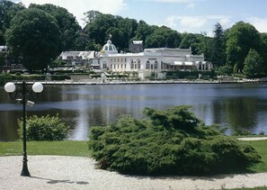 Un grand bâtiment historique doté d’un dôme et d’une architecture classique, situé au bord d’un lac paisible.