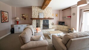 A living room with a stone fireplace, sofas, a coffee table, and a television. - 18th century renovated farmhouse situated in a quiet farming hamlet (Montreuil-Bellay)