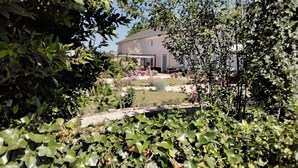 A garden with a pathway leading to a building with a tiled roof. - 18th century renovated farmhouse situated in a quiet farming hamlet (Montreuil-Bellay)