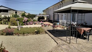 A courtyard with a covered seating area, potted plants, and a gravel path. - 18th century renovated farmhouse situated in a quiet farming hamlet (Montreuil-Bellay)