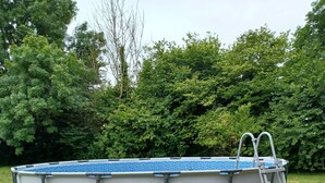 An above-ground swimming pool with a ladder, surrounded by grass and trees. - Le Cosquer farm (Saint-Connec)