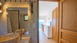 Une salle de bain avec un grand lavabo en pierre, un miroir et un espace douche.