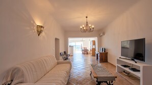 Un salon spacieux avec un canapé, un téléviseur et un coin repas à l’arrière-plan.