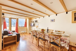 A cozy room with a wooden floor, a dining table set for two, and a sofa.