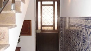 Una escalera que conduce a una puerta con ventanal, pared de azulejos y un sello de fecha.