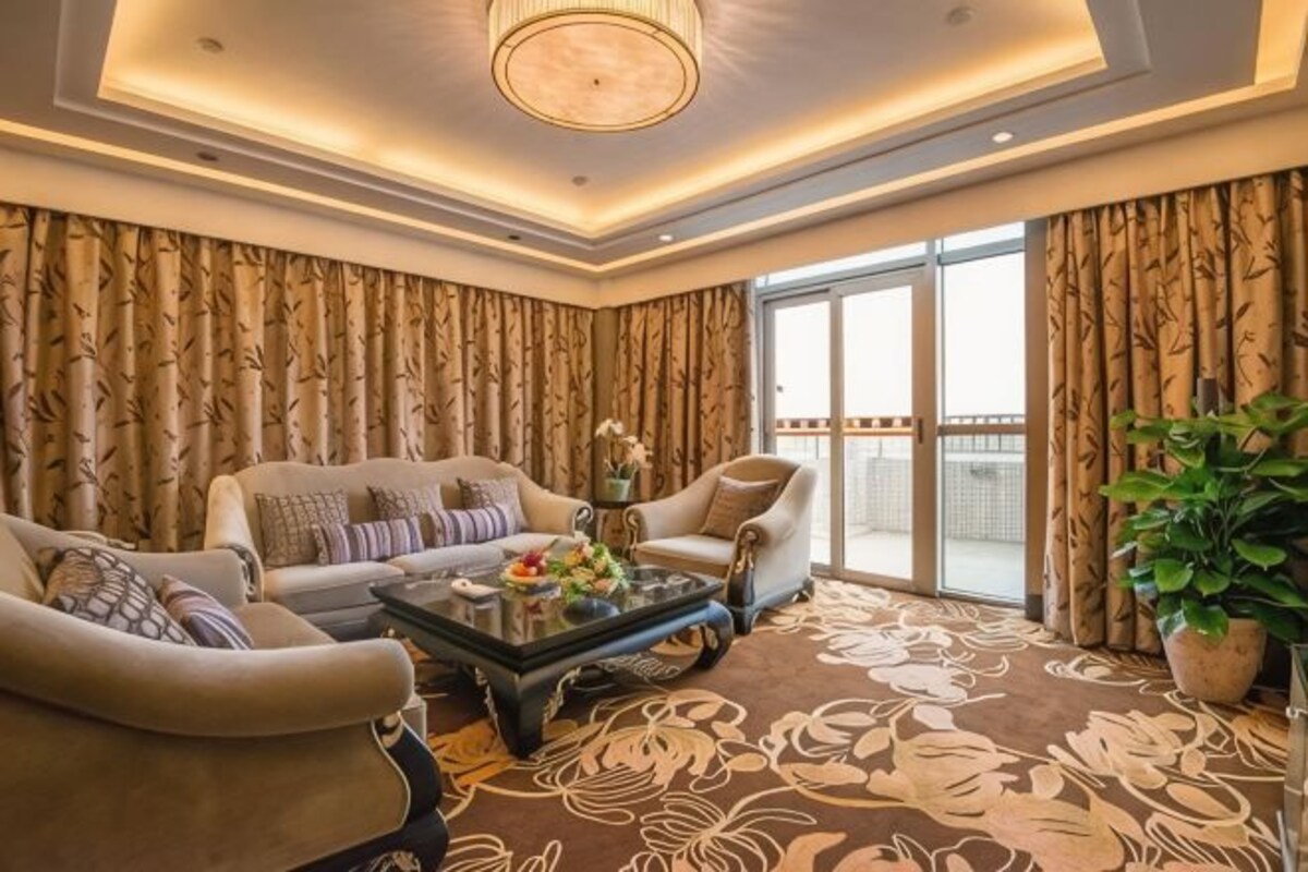 A living room with a sofa, armchairs, a coffee table, and a large window with curtains.