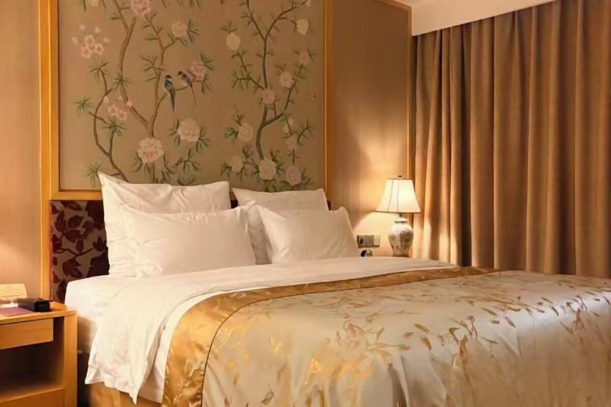 Une chambre d’hôtel avec un lit, une table de chevet, une lampe et une décoration murale florale.