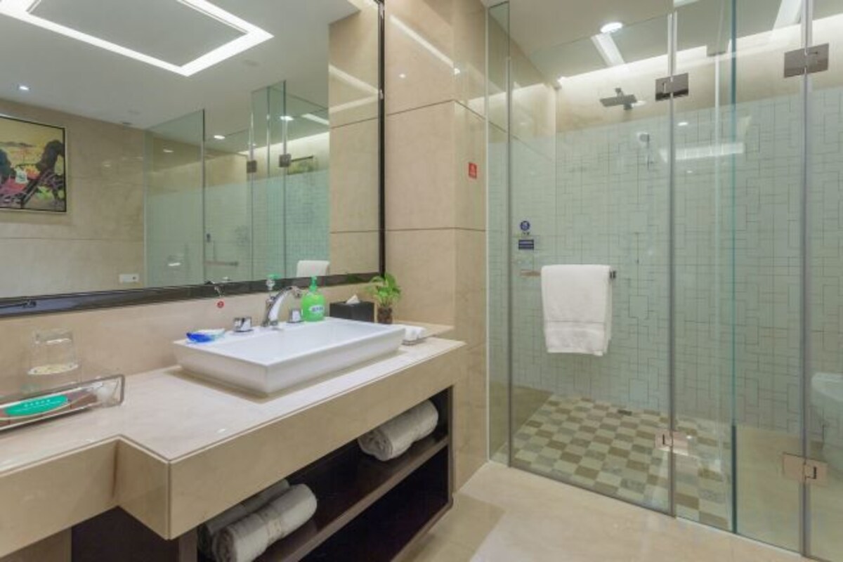 A modern bathroom with a glass-enclosed shower, a large mirror, and a vanity with a sink and towel storage.