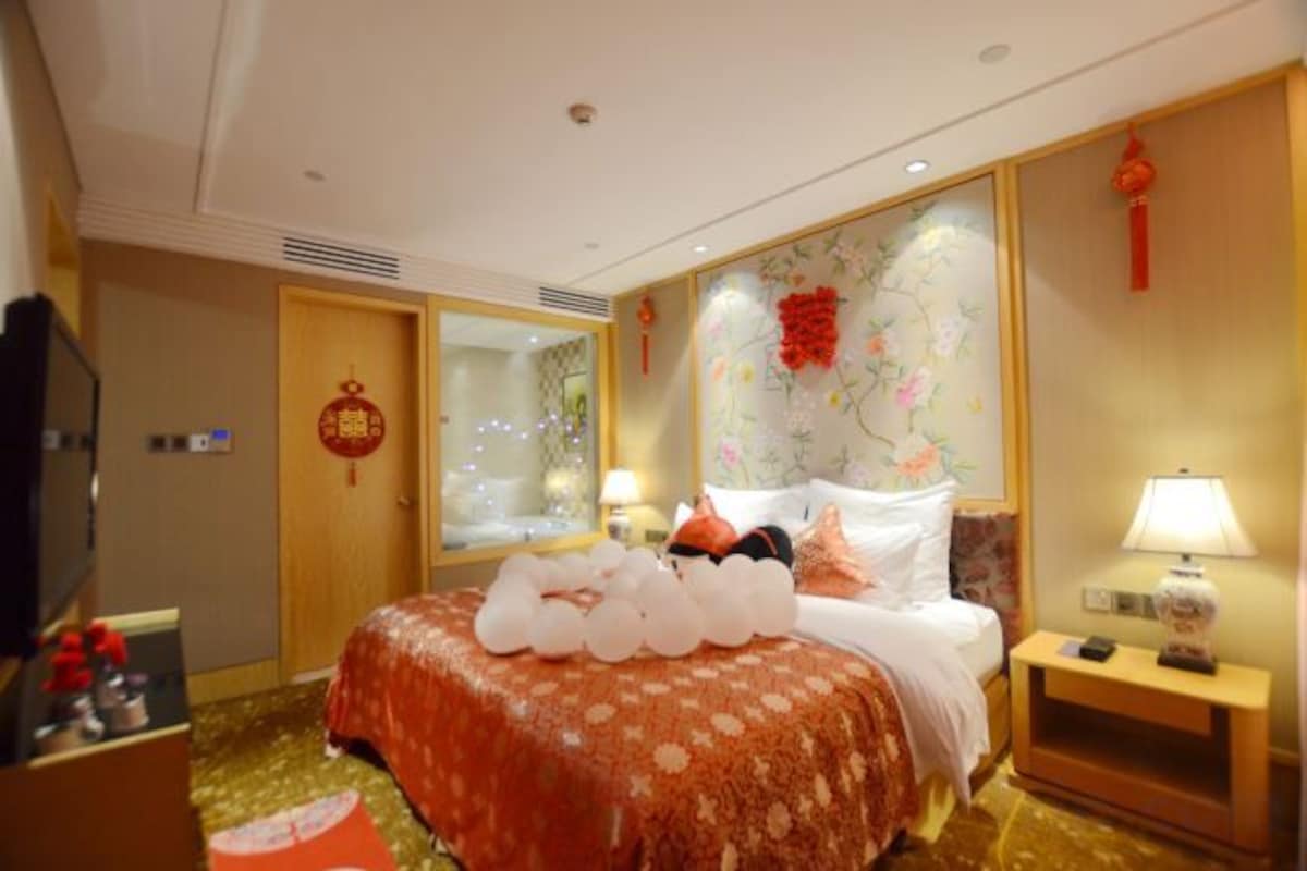 A hotel room with a bed, bedside table, and a television.