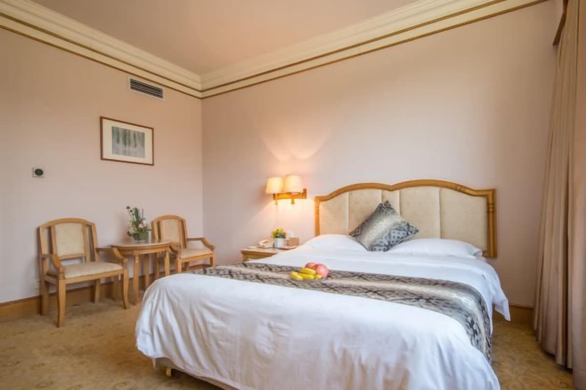 A hotel room with a large bed, two bedside tables, a chair, and a lamp.