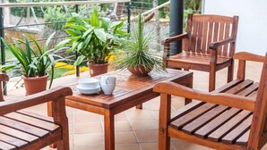 A wooden table and chairs on a balcony with potted plants and a tiled floor. - Villa es Baulo Pleta, with garden and pool near beach (Can Picafort)