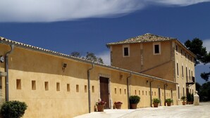 A building with a yellow facade, multiple windows, and a tiled roof. - Villa es Baulo Pleta, with garden and pool near beach (Can Picafort)