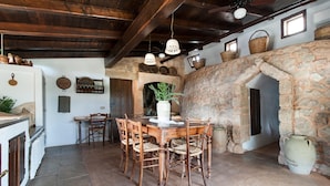 Un comedor rústico con chimenea de piedra, muebles de madera y lámparas colgantes.