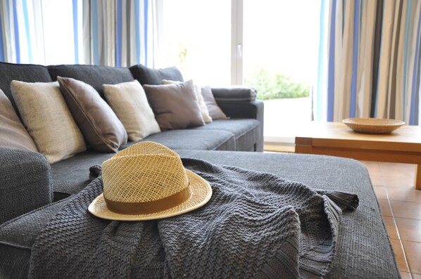 A modern living room with a grey sofa, a woven hat, and a knitted throw.