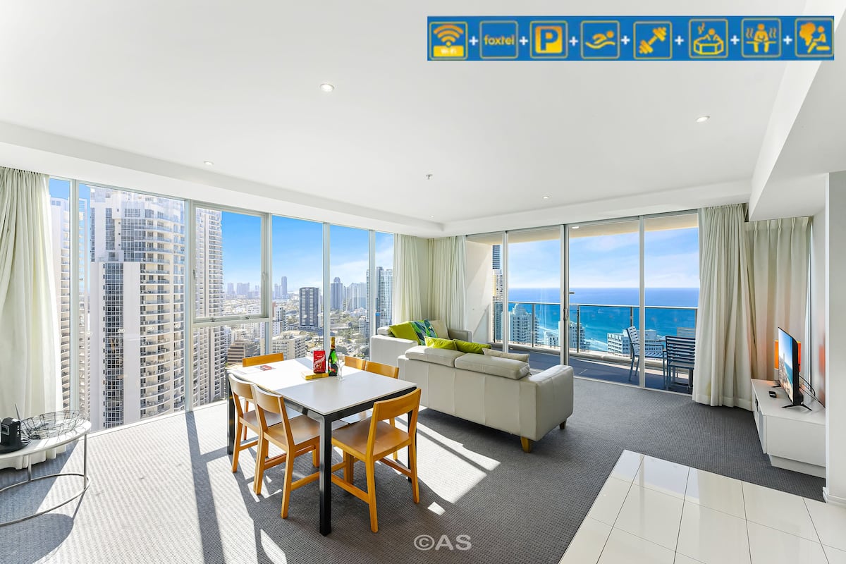 A modern hotel room with a city view, a dining area, and a living space.