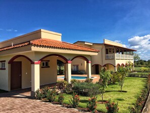 A two-story house with a swimming pool, arched walkways, and a well-maintained garden. - Casa Taylor Gran Pacifica Resort (Villa El Carmen)